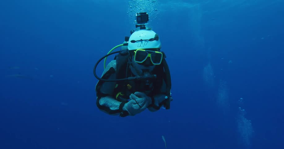 A diver swims under water with a camera on his helmet