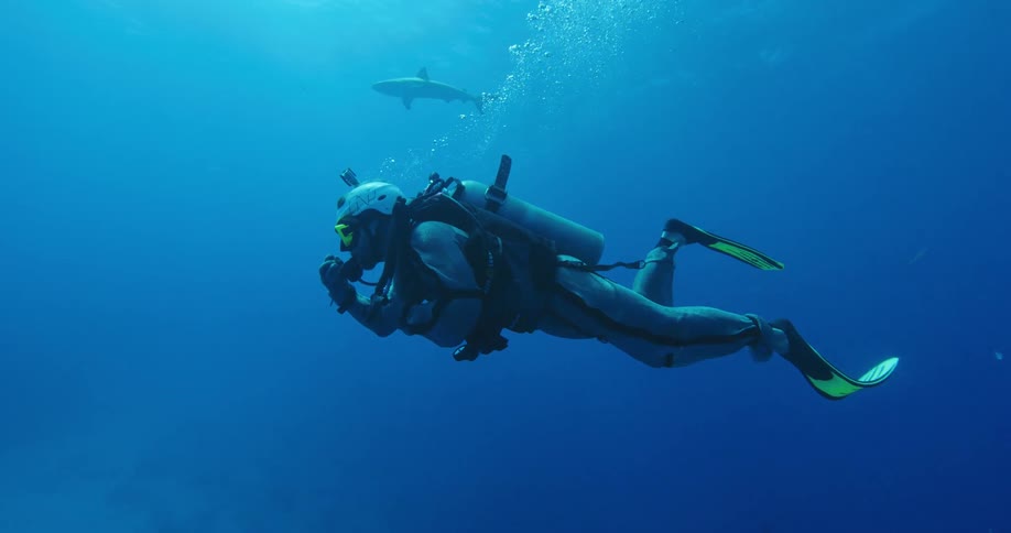 Scuba diver wearing armored suit swimming underwater in the ocean