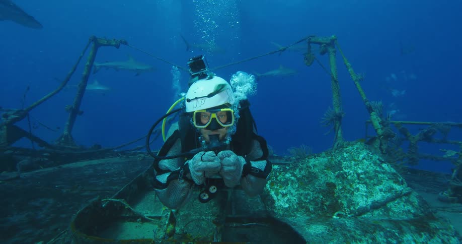 Scuba diver swimming over a sunken ship on the bottom of the ocean