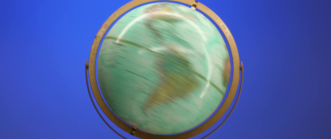 A world globe of earth is on a base spinning with blue colors in the background