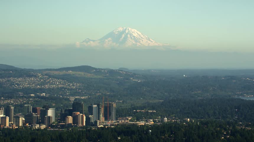 Aerial view of a city in the hills near a snow covered mountaintop in the horizon