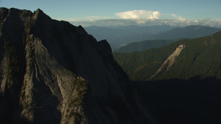 Aerial view of steep rocky mountain and its vast shadow