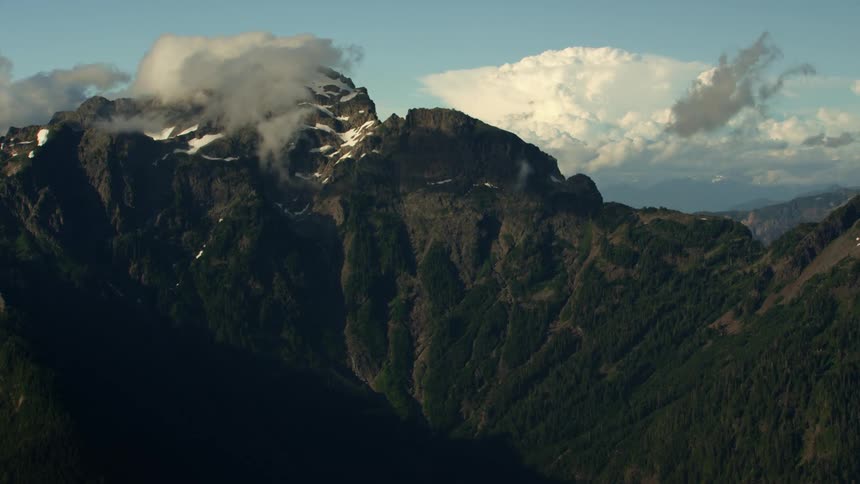 Aerial view of clouds hanging over the snow covered mountain top