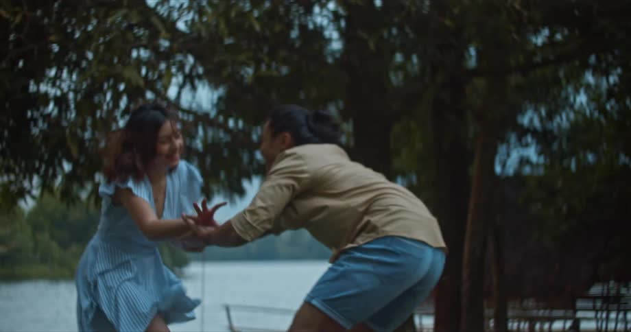 Young happy couple have fun running and holding hands near a lake