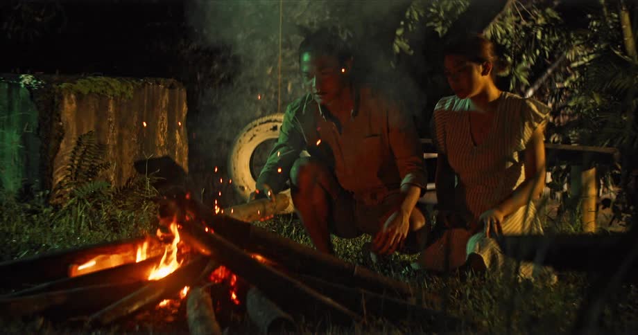 A man stirs the campfire with a log