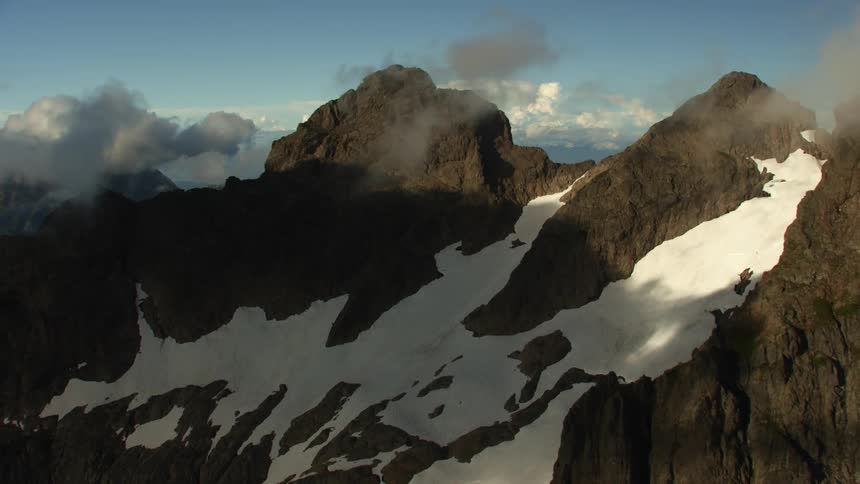 Snow covered mountains with peaks high in the clouds