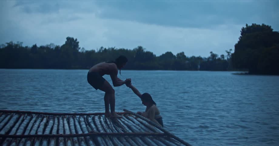 Friends boarding a bamboo raft on a lake in the morning
