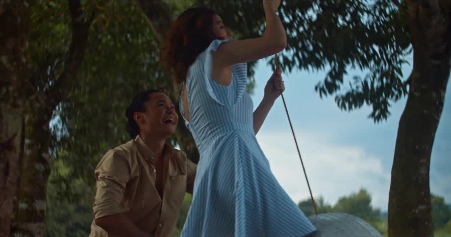 Young happy couple playing in a tire swing near a lake