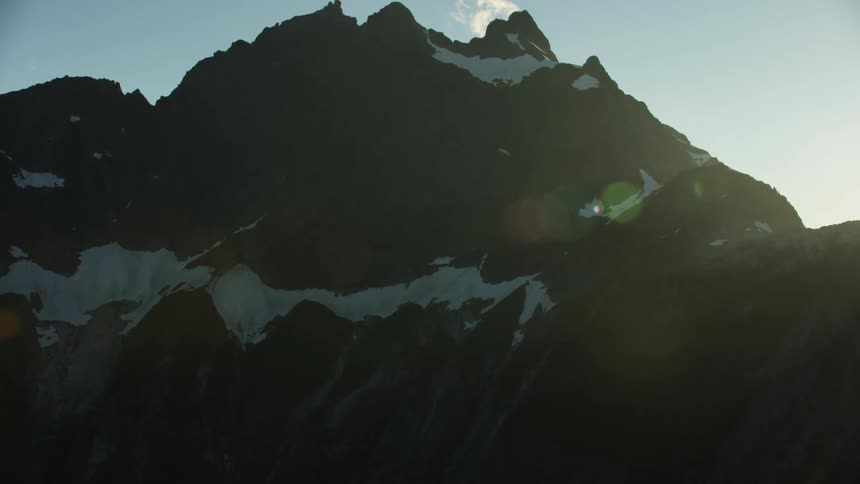 A mountain range with ice and snow with the sky and clouds in the background