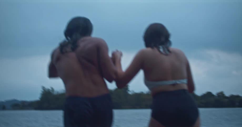 A man and woman jumping into a lake