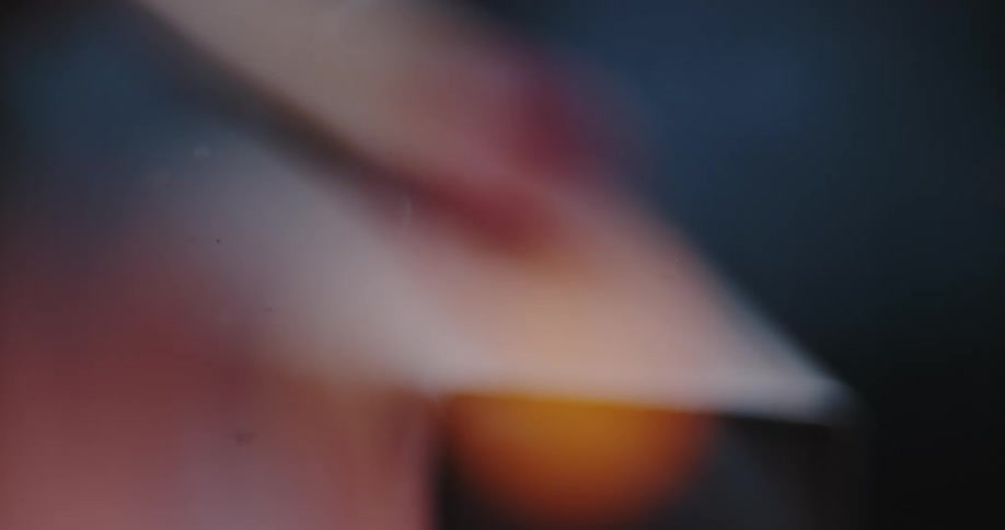 A person strikes a match against its box to ignite a small flame