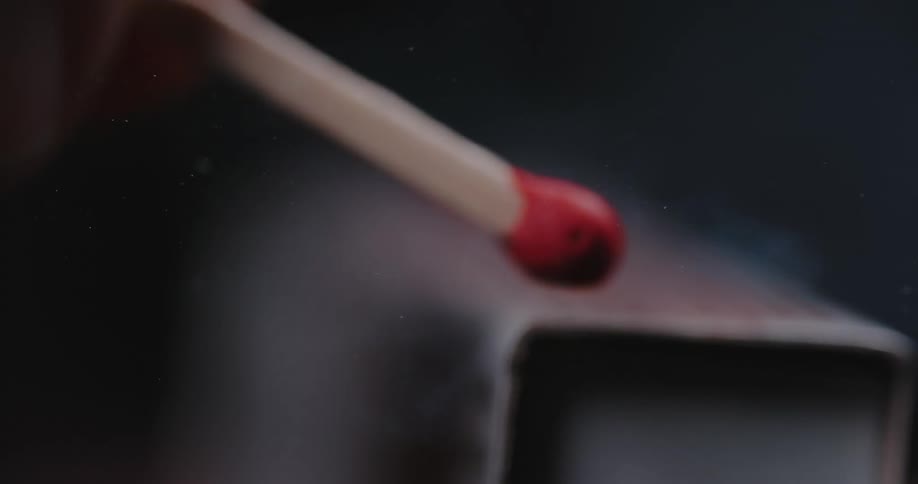 A match striking a matchbox and igniting with fire and smoke