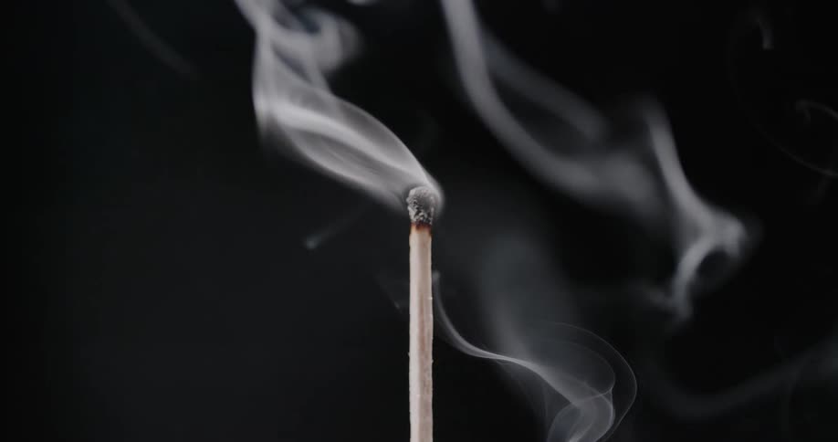 Smoke swirls around the head of a burned out wooden matchstick