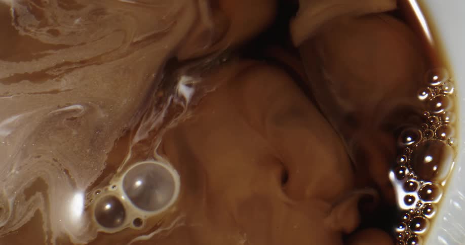Milk splashing on a white ceramic cup of black coffee