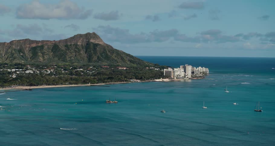 An aerial view of boats in the sea and a skyline in the distance