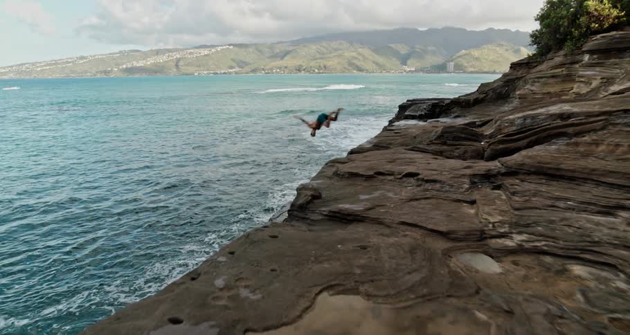 A man is diving off the coast into the ocean