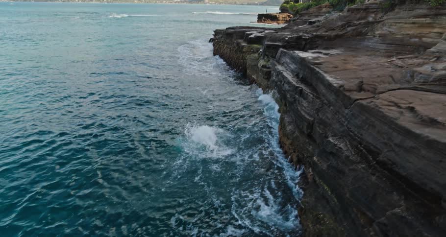 A man runs and dives off the cliff into the water