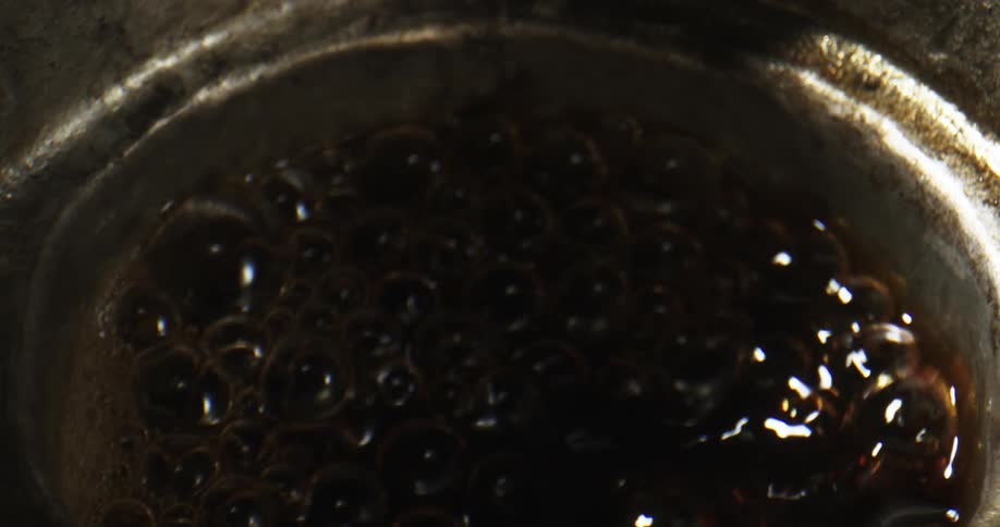 Coffee being boiled and bubbling in a pot and milk being added to it