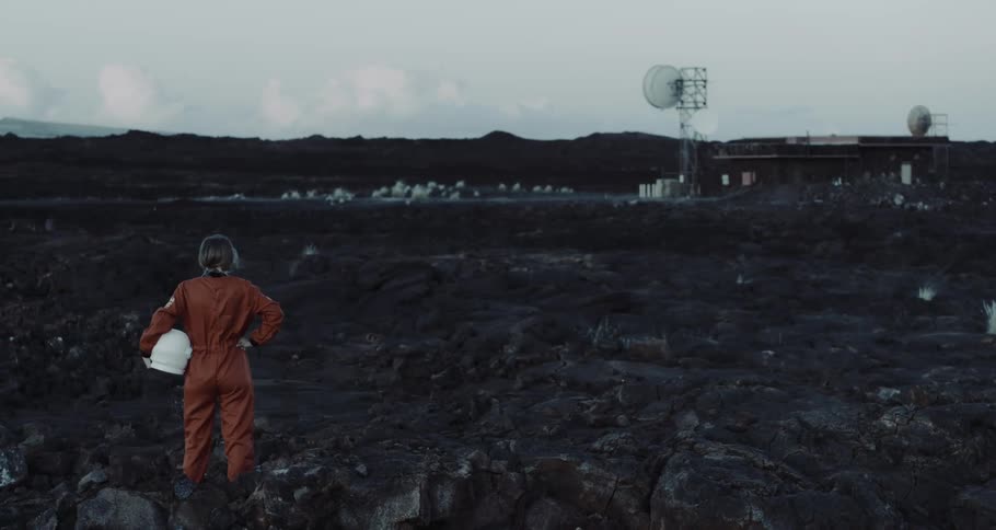 A person with a spacesuit in a landscape with satellite dishes with the sky and clouds in the background