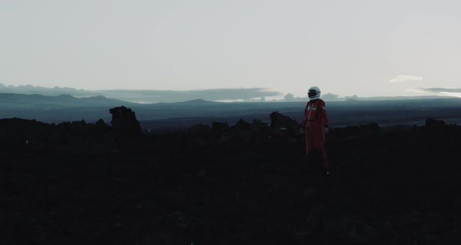 A person in an astronaut suit is walking past the rocks