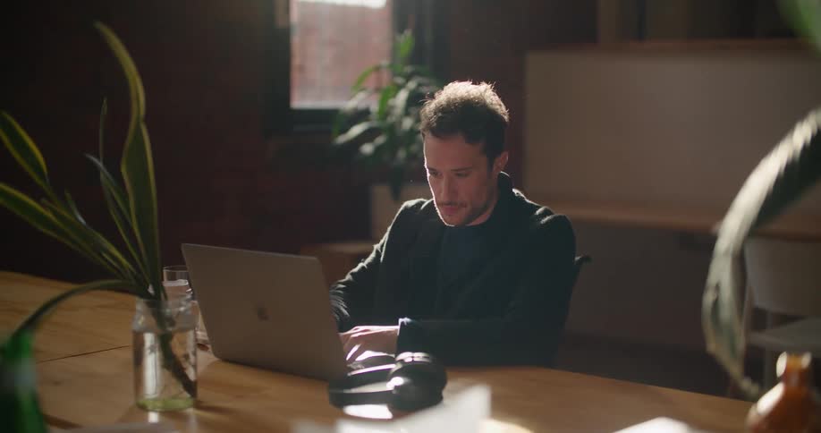 A man is contemplating as he works in front of a laptop