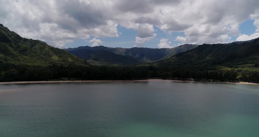 Lake surrounded by forested mountains under a cloudy sky