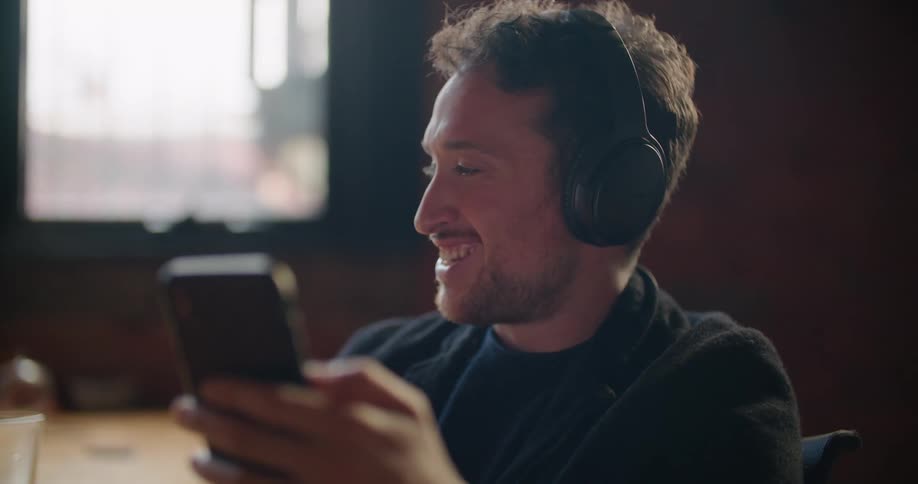 A man is laughing as he seems to be talking on a video call on his phone