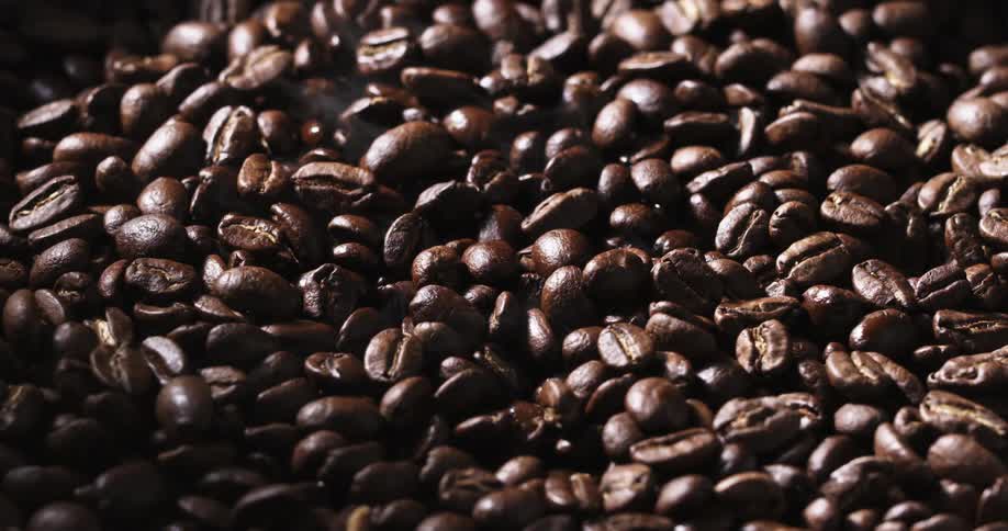 Steam rises from roasted coffee beans