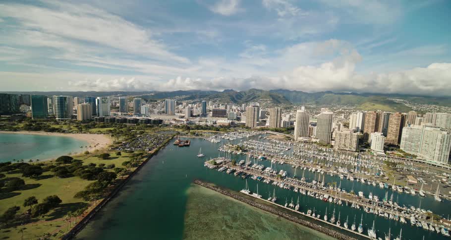 An aerial view of high rise buildings in a skyline on the coast and boats parked at the dock in the water