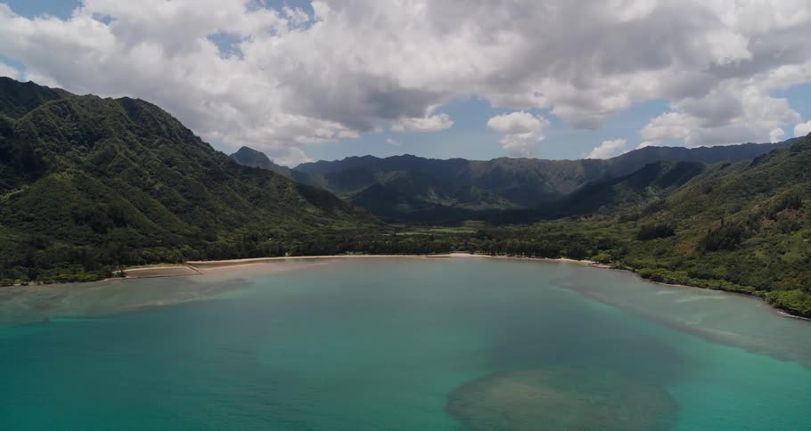 A coastal beach with sand and water with the sky and clouds in the background