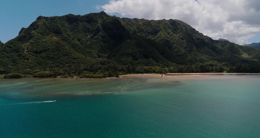 Aerial view of an ocean next to mountains is displayed