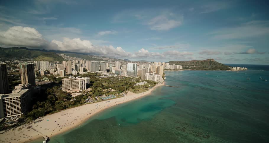 Crowds of people relax on the beach and at the pool at luxury resorts on the coast