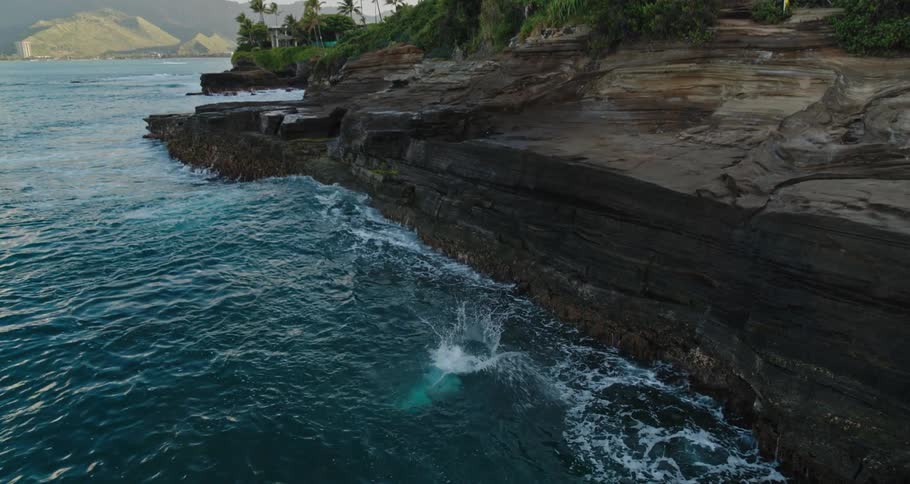 A man runs and jumps off the edge of a cliff in to the water