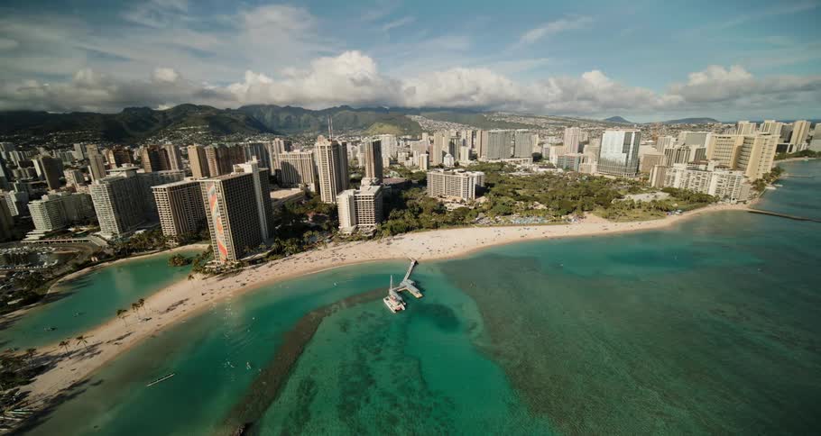 A beach with sand with buildings the sky and clouds in the background