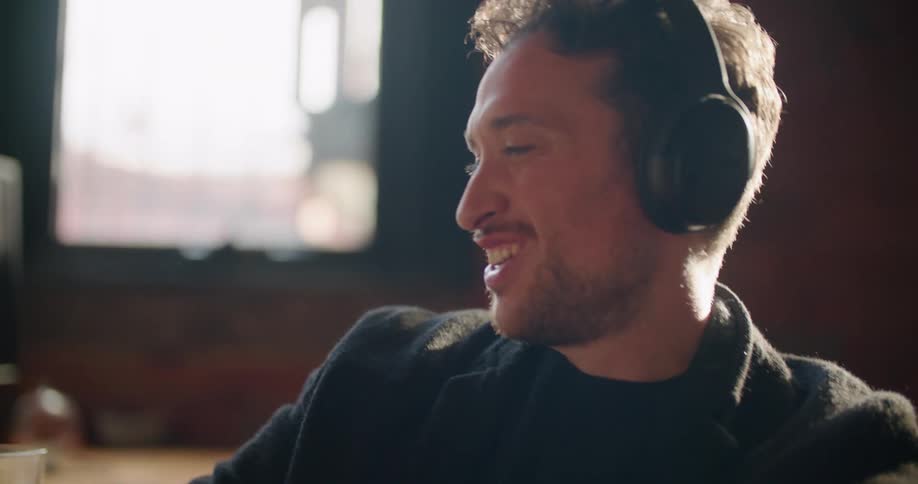 A man laughs and nods his head while talking to a friend via video call on his laptop