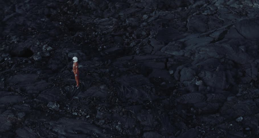 Aerial view of a person wearing an astronaut suit on a rocky terrain