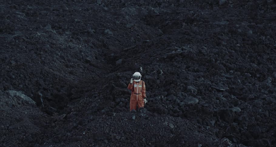 Person wearing helmet and jumper stands on vegetation free uneven terrain