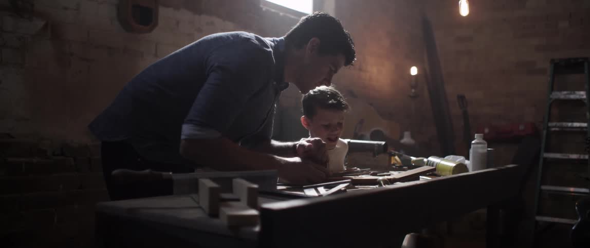 Men showing a young boy some tool skills in a workshop