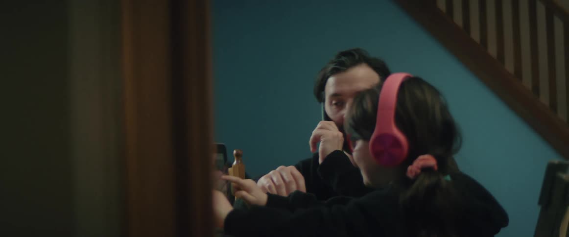 A man talks on the phone and then walks over to his daughter as she shows him her laptop screen