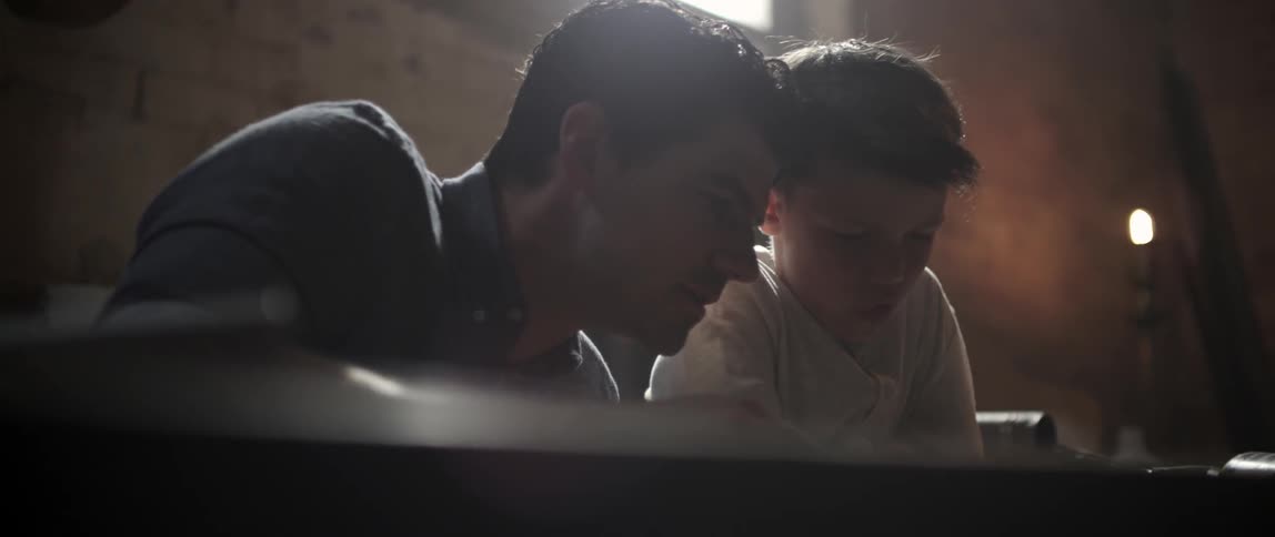 Man demonstrating his craft to a young boy and a workshop