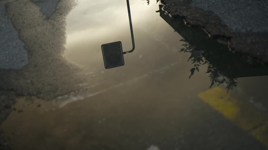 Puddle in parking lot reflects street lamp