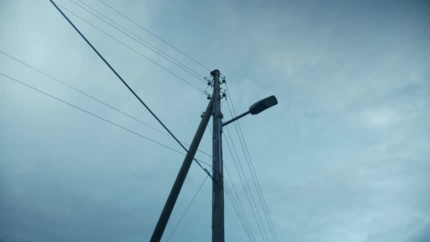 Numerous cables and a street lamp extend from a utility pole
