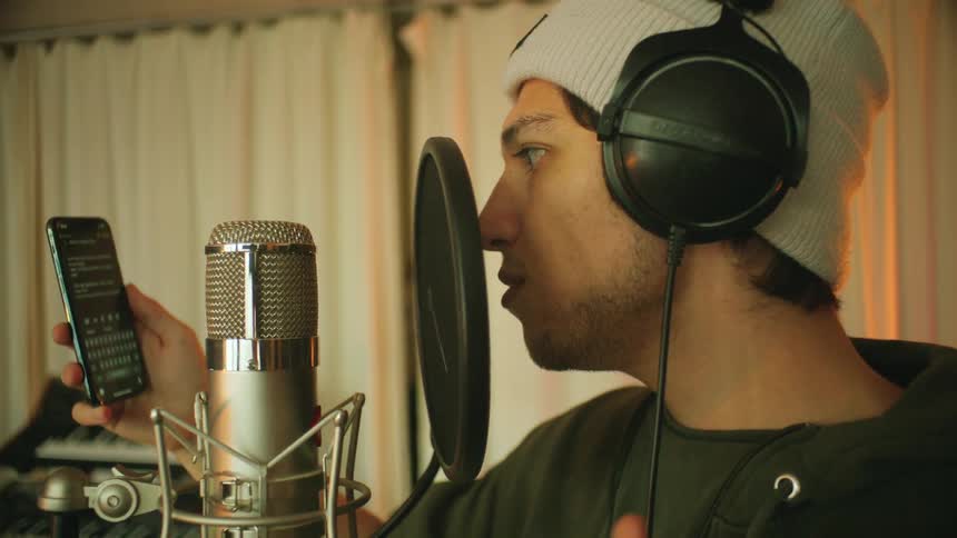 A man looks at his phone as he prepares to sing into a microphone