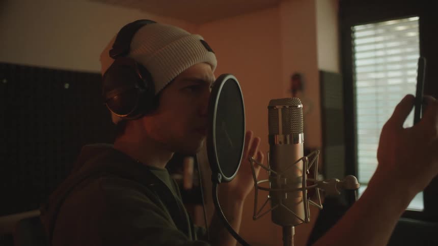 A man looks at a phone as he gets ready to sing into a microphone