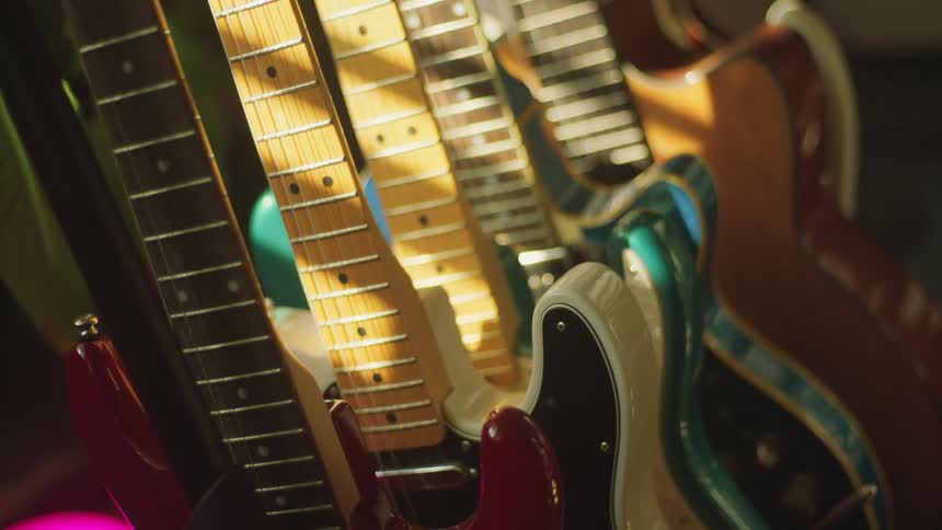A room with guitars with a wall in the background