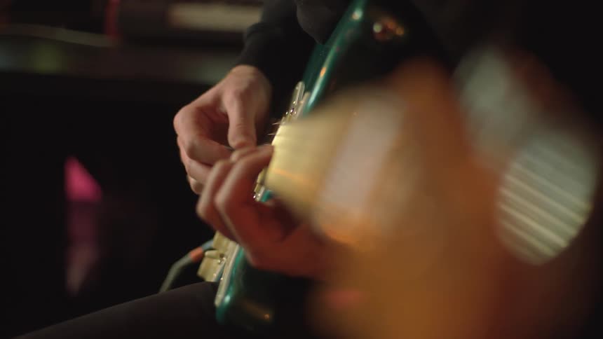 A close up of a mans hands playing an electric guitar