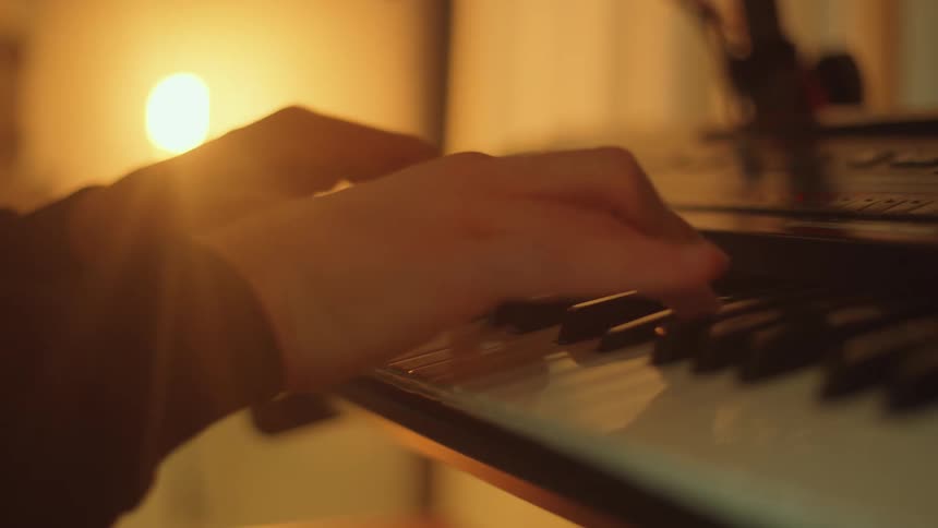 Person plays electric piano next to lamp in the studio
