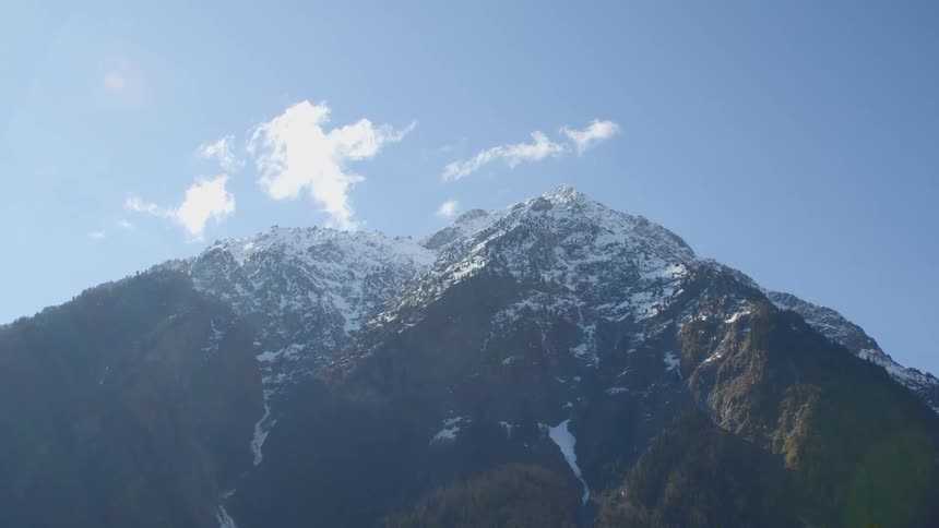 A light dusting of snow covers the top of a mountain