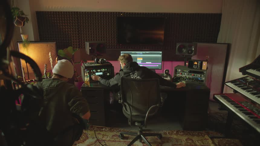 Two men are sitting in a music studio