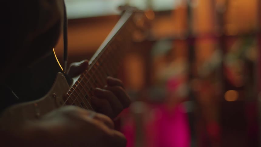 Close up of a mans fingers as he plays a song on guitar